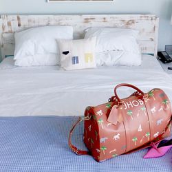 Red luggage bag on white bed in bedroom