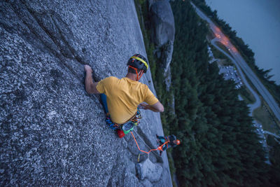 Top view man rock climbing at sunset above the sea and highway