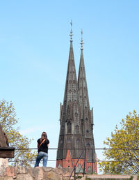 Rear view of woman standing by uppsala cathedral against clear blue sky