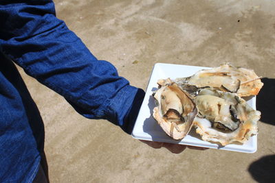 Midsection of person holding seafood standing outdoors