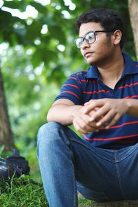 Young man looking away while sitting outdoors