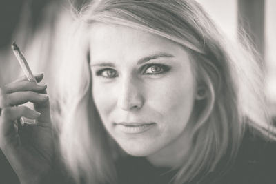 Close-up portrait of woman smoking marijuana joint at home