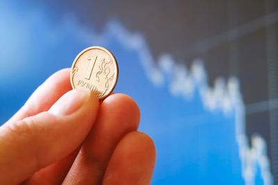 Close-up of hand holding crystal ball against blue background