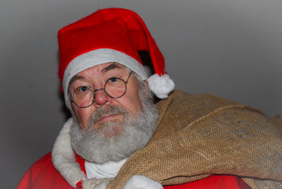 Portrait of man wearing santa costume against wall