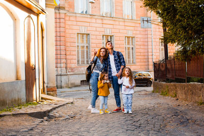 Full length of father with daughter standing against wall