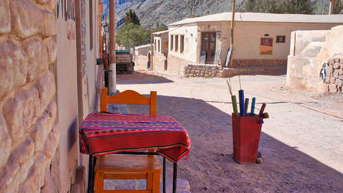 Empty chairs and tables in street against building