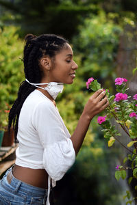 Young woman takes face mask off to smell the flowers