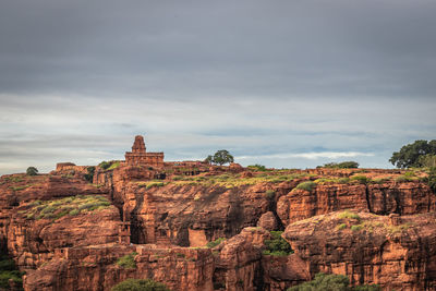 Rock formations on landscape against cloudy sky