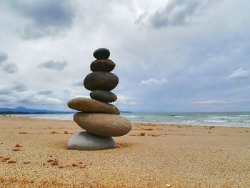 Stack of pebbles on beach against sky