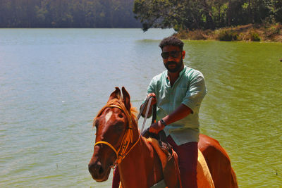 Portrait of young man with horse in lake