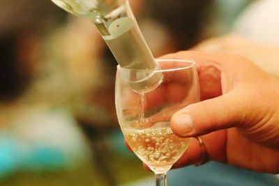 Close-up of hand pouring wine in glass