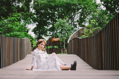 Full length of woman sitting footpath