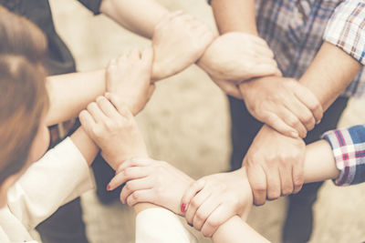 Midsection of people holding hands while showing unity