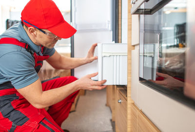 Repairman repairing refrigerator at home