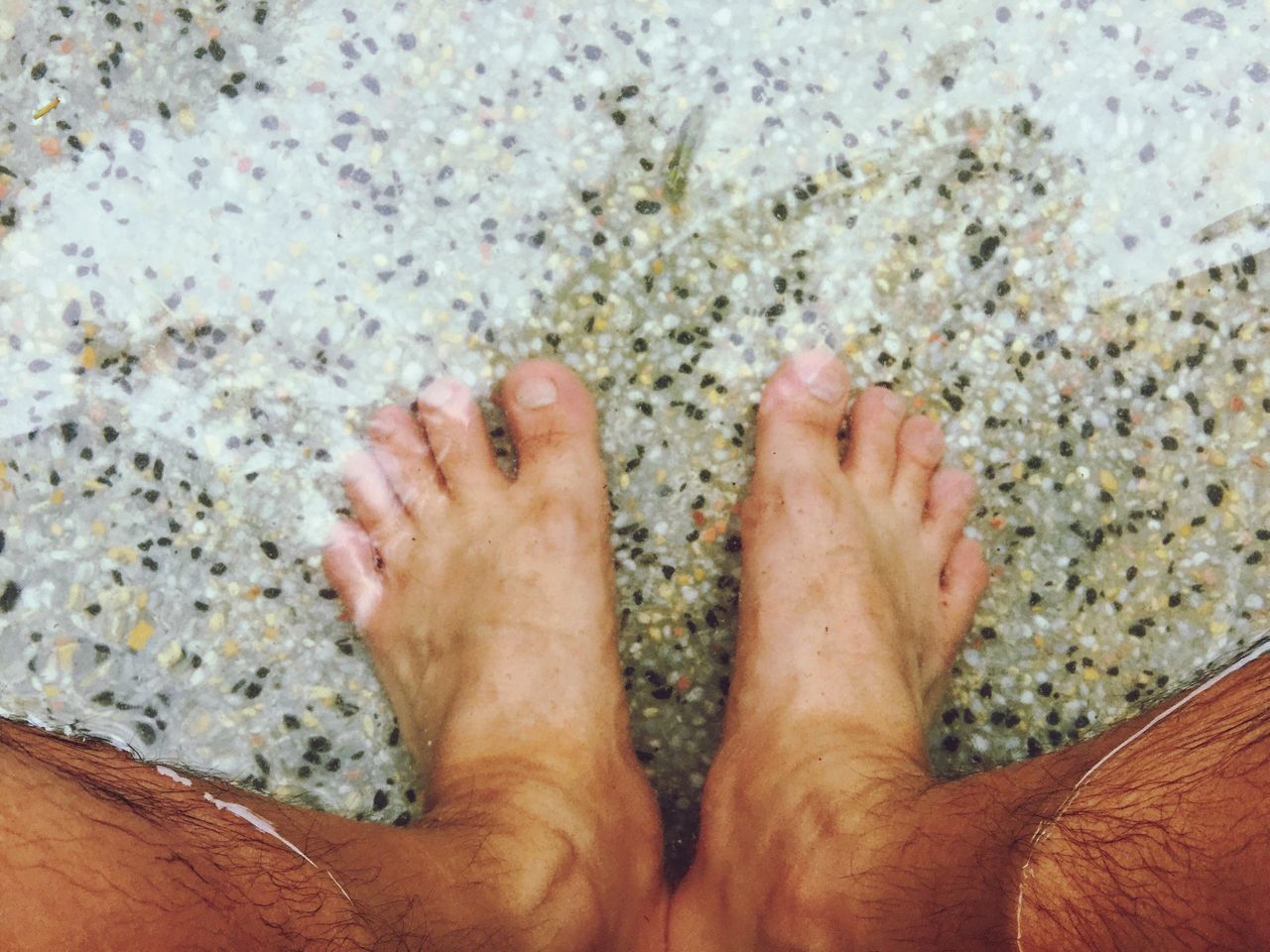 LOW SECTION OF MAN LYING ON SAND