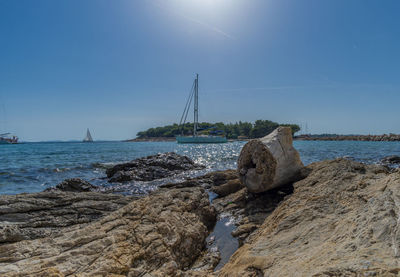 Sailboat on sea shore against sky