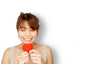 Portrait of woman holding strawberry over white background