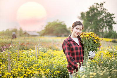 Young woman with yellow flowers on field