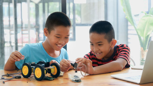 Brothers making toy car on table at home