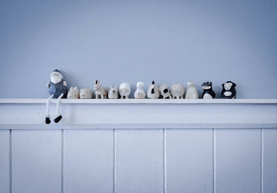 Low angle view of birds perching on railing against white wall