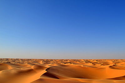 Scenic view of desert against clear blue sky