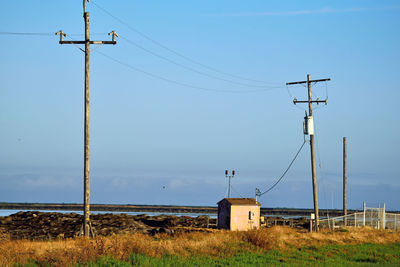 Electricity pylon on field against clear sky