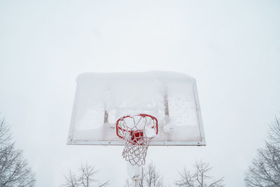 Low angle view of basketball hoop against sky during winter