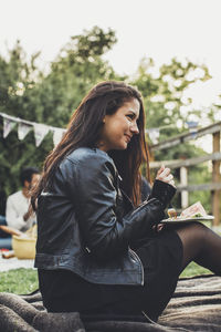 Side view of woman having breakfast during rooftop party