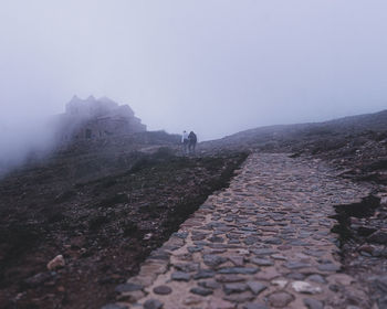 People walking on mountain against sky