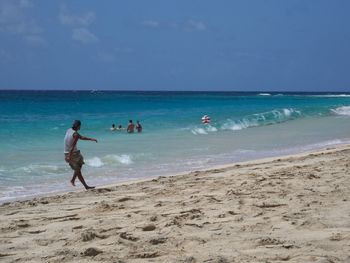 People enjoying on beach against sky