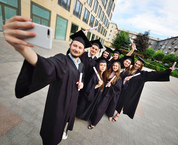 Happy friends wearing graduation gown