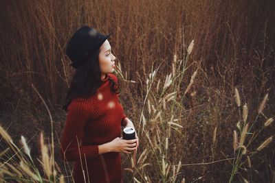 Young woman looking away while standing on field