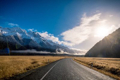 Road by mountains against sky during winter