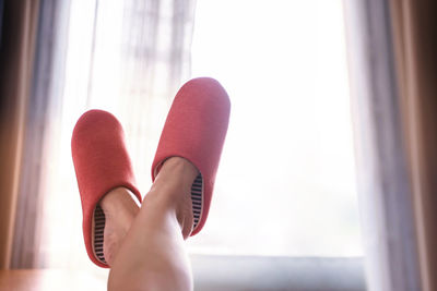 Low section of woman wearing shoes at home