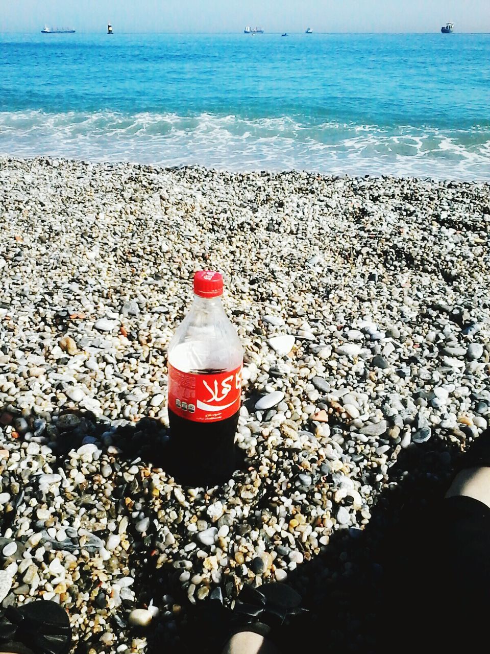 sea, horizon over water, beach, water, shore, red, sand, lifestyles, rock - object, pebble, beauty in nature, tranquility, nature, stone - object, scenics, high angle view, leisure activity, vacations