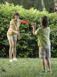 Mother and son play frisbee on grass lawn. summer vibes. outdoor leisure activity. 