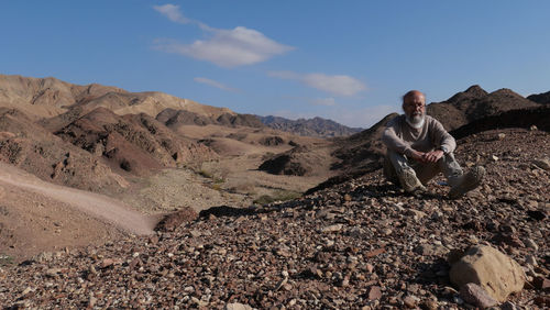 Senior man sitting on rock in the desert 