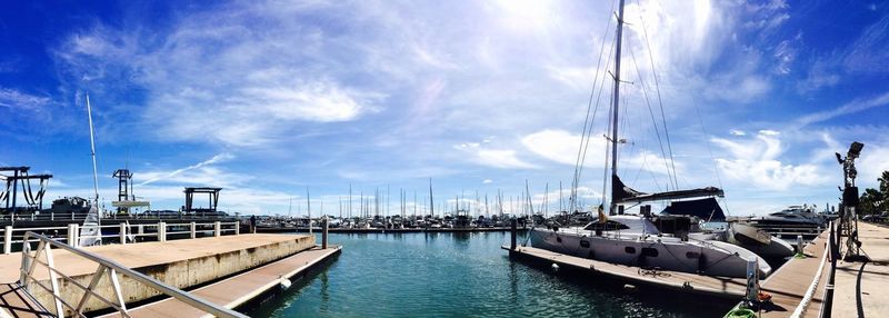 Boats in harbor against cloudy sky