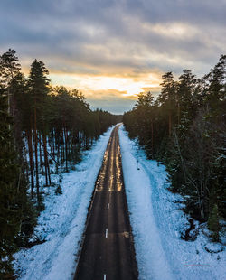 Road amidst trees against sky during sunset