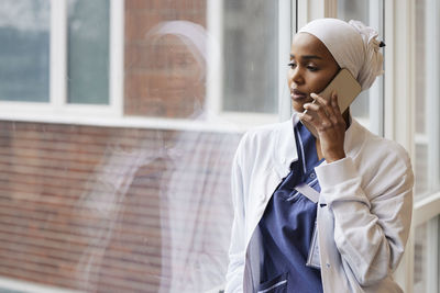 Young female doctor talking on phone at work