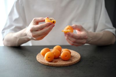 Cropped image of man holding orange fruits