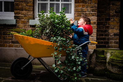 Side view of boy holding umbrella against plants