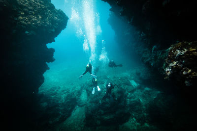 High angle view of people scuba diving amidst rock formations in sea at ishigaki