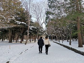 Rear view of women walking on snow covered trees