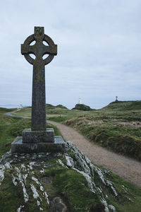 Cross on field against sky