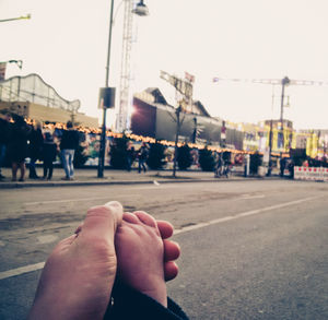 Midsection of woman holding hands on road against sky