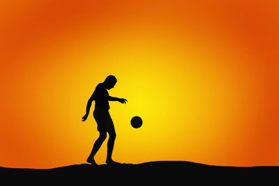 Silhouette man playing soccer against clear orange sky