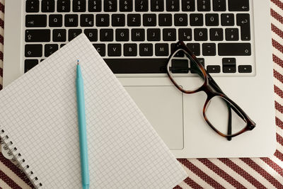 High angle view of laptop with book and pen on table