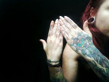Cropped image of punk woman with tattoos against black background