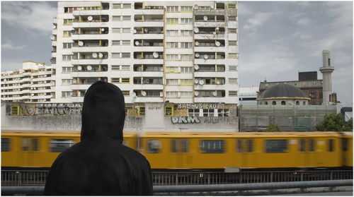 Blurred motion of train and buildings in front of person in city